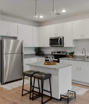 spacious kitchen with stainless steel appliances and island with two stools