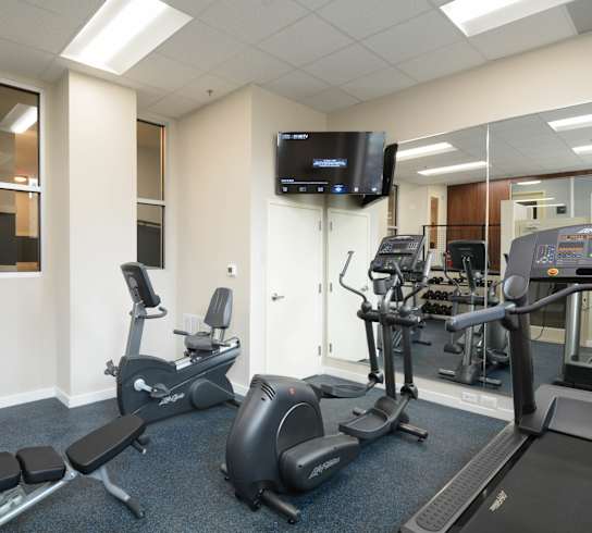 a room filled with lots of exercise equipment and a flat screen tv