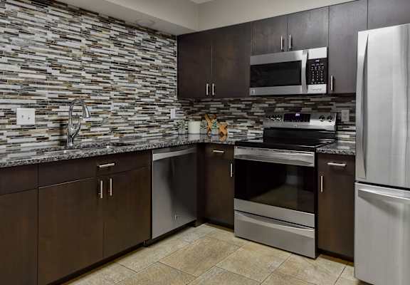 a kitchen with stainless steel appliances and wooden cabinets at The Pointe at St. Joseph Apartments, South Bend, IN, 46617