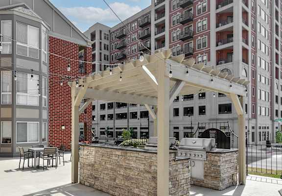 a patio with a grill and a pergola in front of a building at The Pointe at St. Joseph Apartments, South Bend, IN, 46617