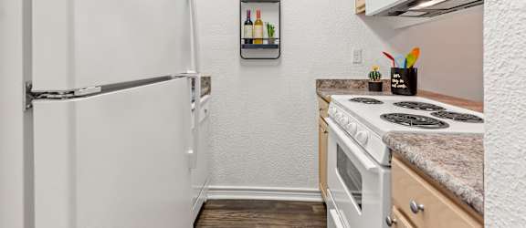 A small kitchen with a white refrigerator and a white stove.