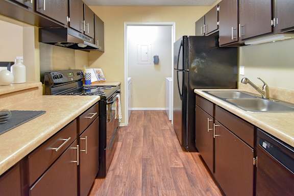 A kitchen with brown cabinets and a black refrigerator.
