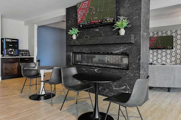 A black table with four chairs in front of a fireplace.