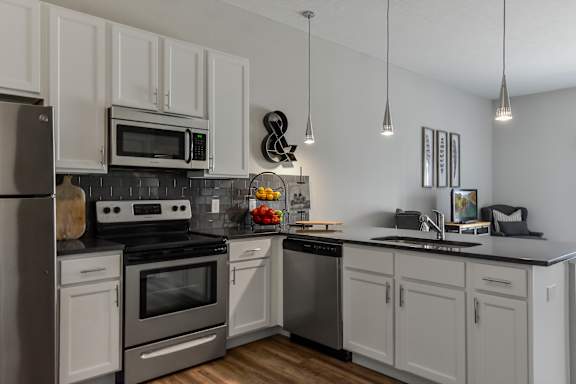 an apartment kitchen with stainless steel appliances and white cabinets