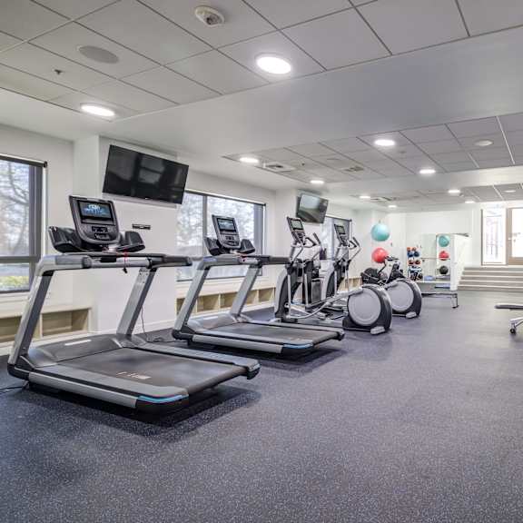 a gym with treadmills and other exercise equipment in a building with windows