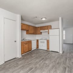 Kitchen with white appliances and wooden cabinets at Greens of Concord, North Carolina, 28025