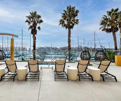 A row of chairs with cushions are lined up on a patio.