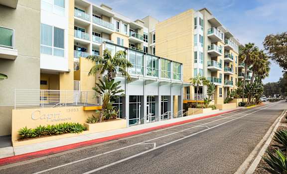A street view of a Cayman Apartments building with a clear blue sky above.