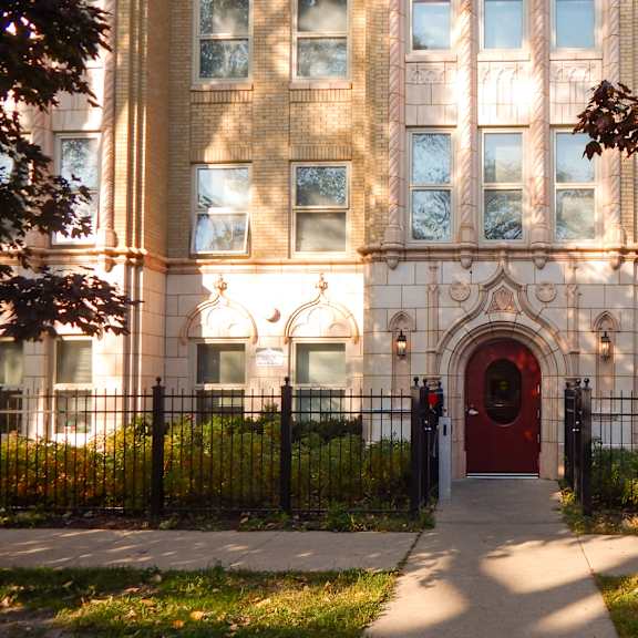 A building with a red door and a black fence.