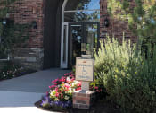 Thumbnail 38 of 40 - Westlake Greens Leasing Office brick front entrance with green plants and flowers