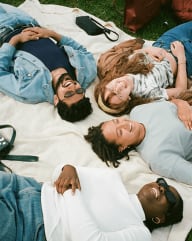 a group of people laying on a blanket on the grass