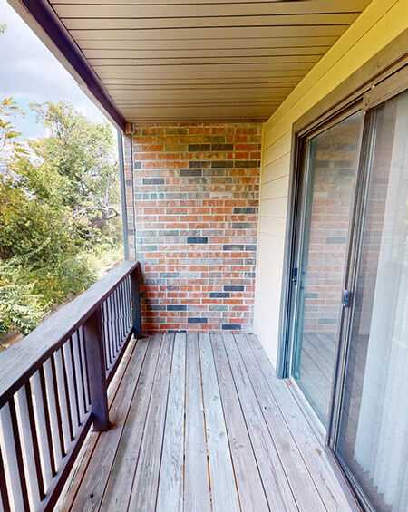 a balcony with a sliding glass door and a brick wall