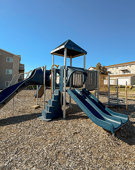 A playground with a blue slide and a wooden structure.