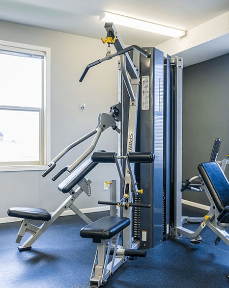 A gym with a weight machine and a window.