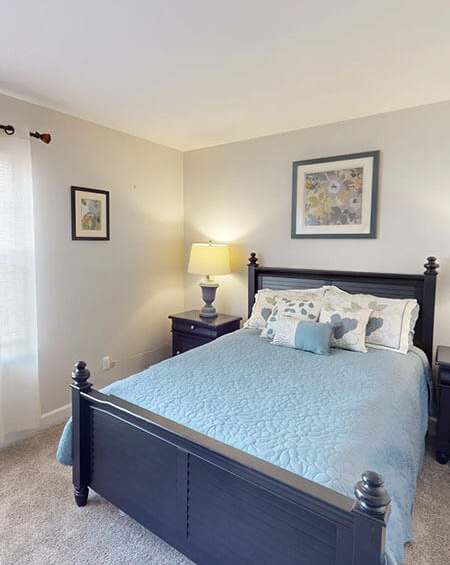 A bedroom with a large bed and two pictures on the wall.