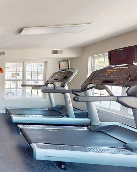 A treadmill in a gym with a monitor on top.