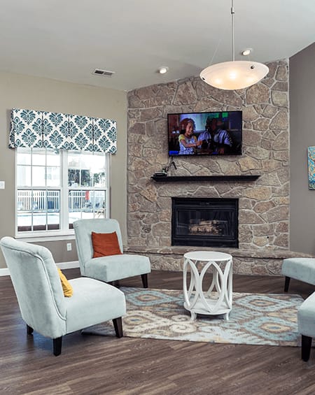 a living room with a stone fireplace and a tv above it