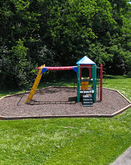 A playground with a yellow slide and a red and green play structure.