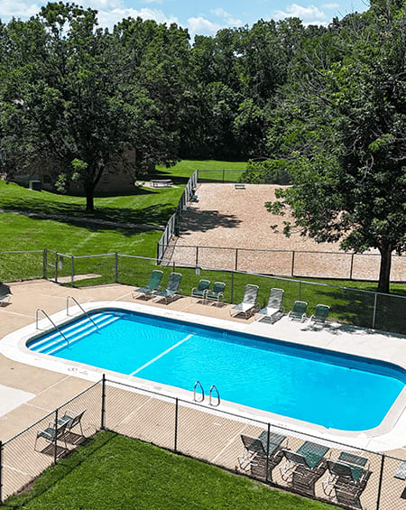 A pool surrounded by a fence and chairs.