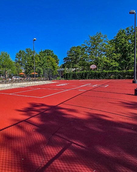 a red tennis court with trees in the background