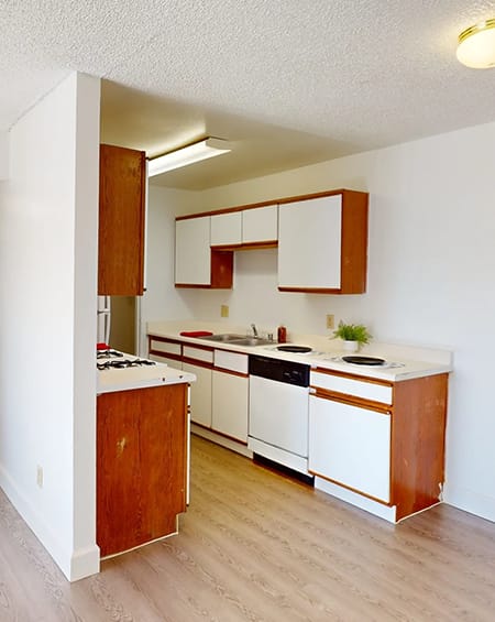 an empty kitchen with white appliances and wooden cabinets