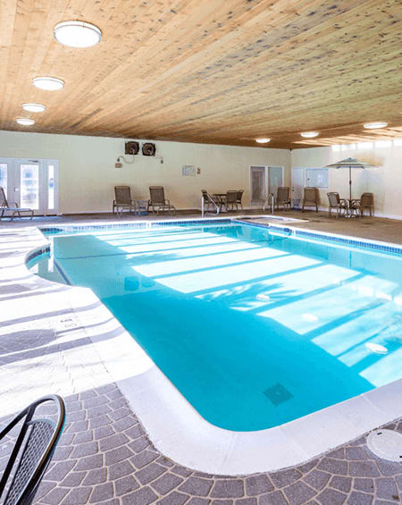 A large indoor swimming pool with a wooden ceiling and tiled floor.