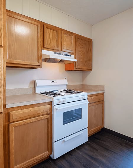 A white stove in a kitchen with wooden cabinets.