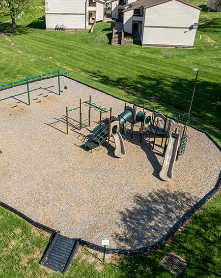 A playground with a green swing set and a slide.
