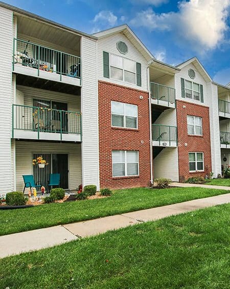 an apartment building with two balconies and a sidewalk
