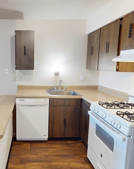 A white dishwasher and oven in a kitchen with wooden cabinets.