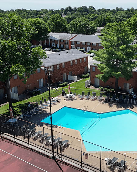 A pool surrounded by chairs and trees in front of a building.