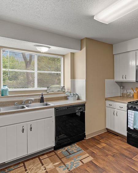 an empty kitchen with white cabinets and a window