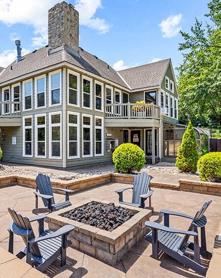 a patio with chairs and a fire pit in front of a house