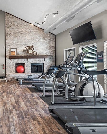 a gym with weights and a television on the wall