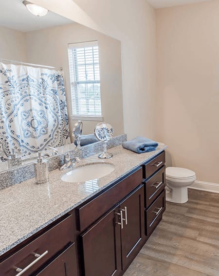 A bathroom with a sink, toilet, and a window.