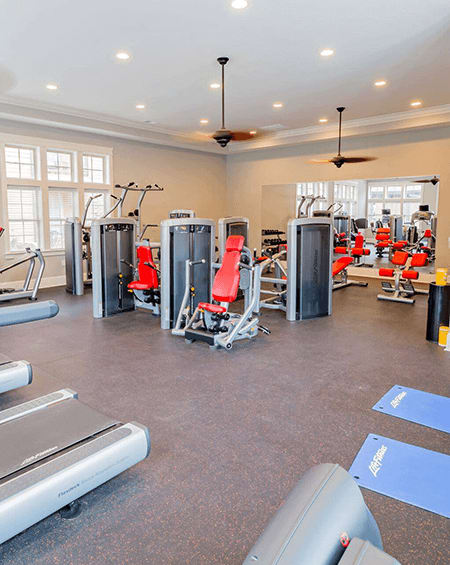 A gym with a variety of equipment including treadmills, weights, and exercise machines.