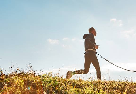 a man walking his dog on a leash in a field