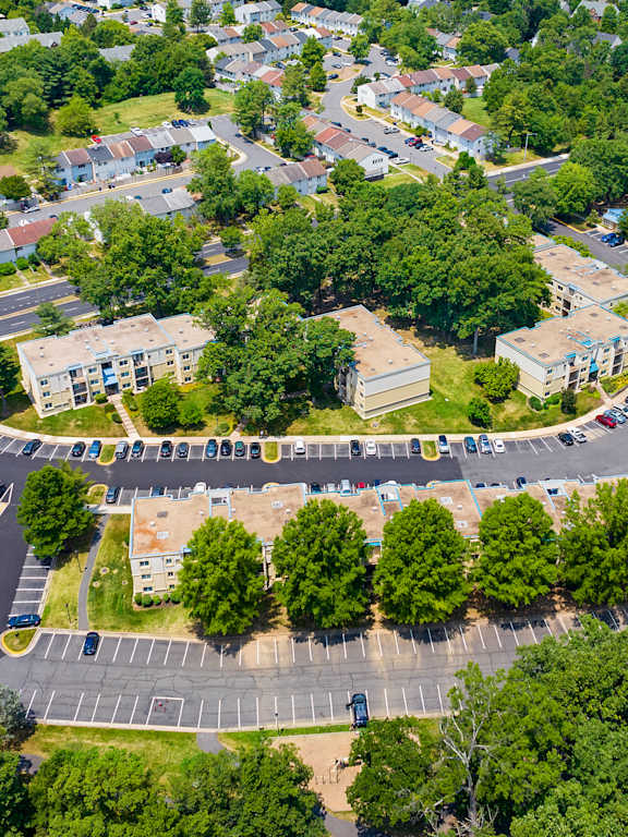 an aerial view of a parking lot with trees and buildings
