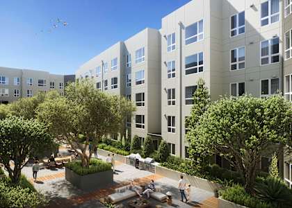 A courtyard with a fountain and people sitting on benches is surrounded by apartment buildings.