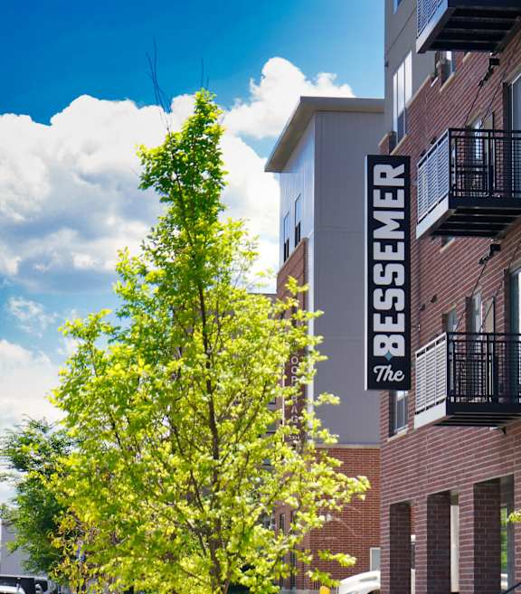 A tree in front of a building with a sign that says Bessemer at The Bessemer at Seward Commons Apartments, Minneapolis, 55404