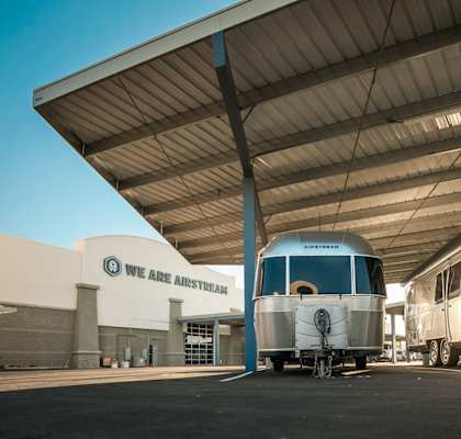 Two silver airstreams parked under an outdoor covered space next to a building with the words We Are Airstream.