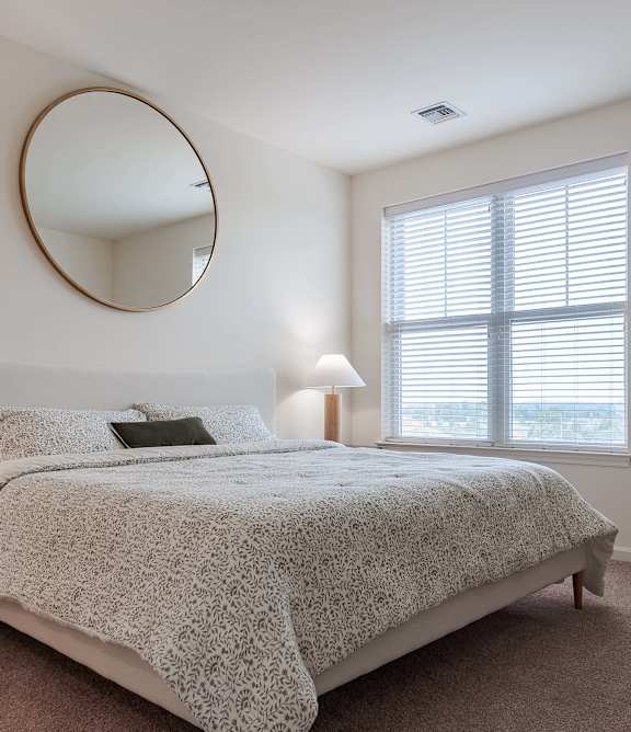 A bedroom with a round mirror on the wall.