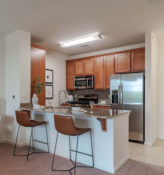 A kitchen with a white countertop and brown chairs.