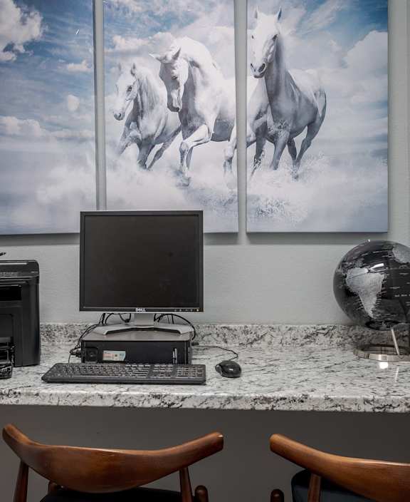 a desk with a computer and three pictures of horses on the wall