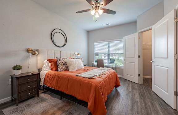 A bedroom with a bed, nightstand, and a ceiling fan.