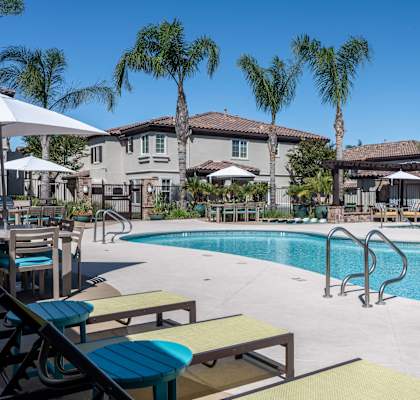 a swimming pool with tables and chairs and palm trees