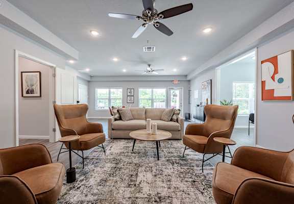 A living room with brown chairs and a grey rug.