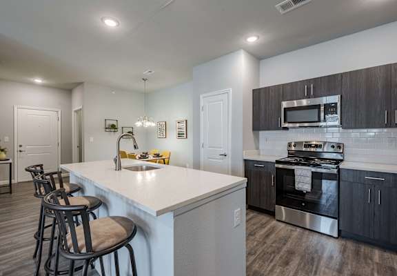 A kitchen with a white countertop and black bar stools.