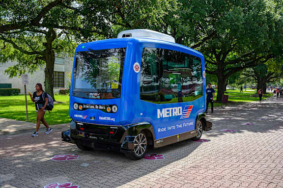 A blue Metro bus is parked on a brick road.