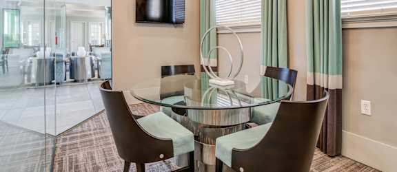 a dining room with a glass table and chairs and a television